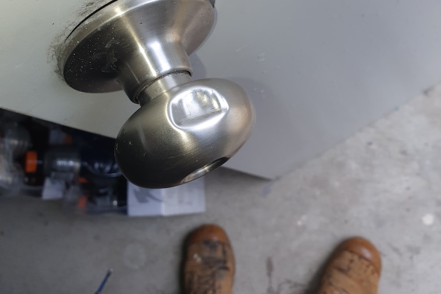 An adult's perspective view looking down at a doorknob.