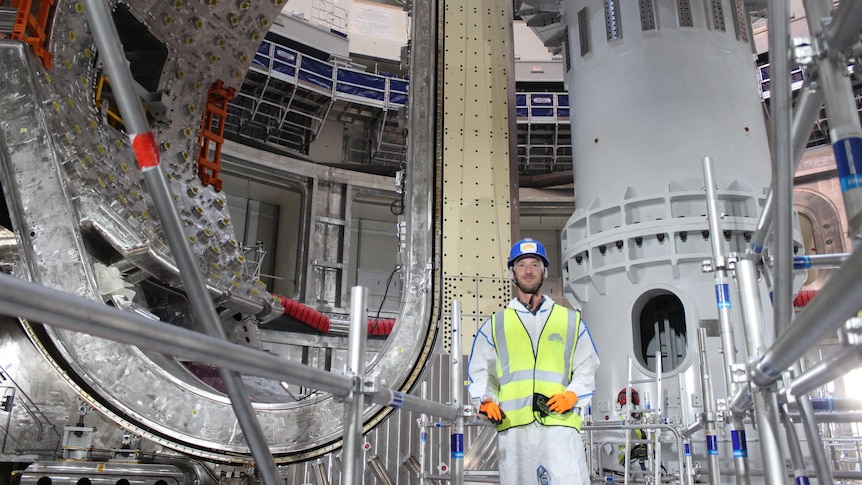A worker is dwarfed by massive infrastructure showing the immense size of the ITER nuclear fusion reactor  under construction.