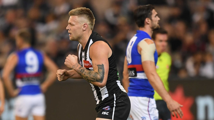 A player celebrates an AFL goal as an opponent walks away.