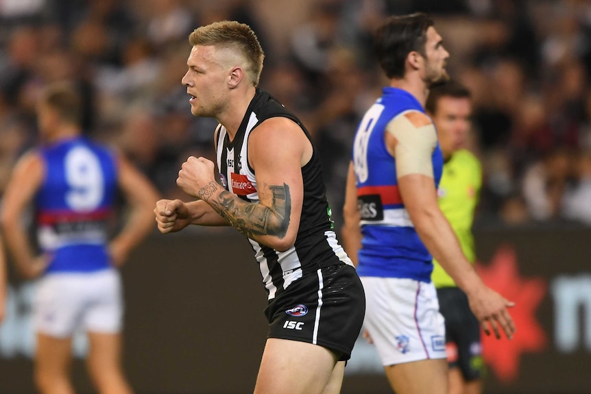 A player celebrates an AFL goal as an opponent walks away.