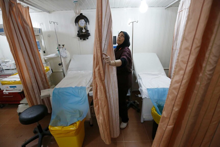 Um Hassan moves the curtains around her bed in the Zaatari refugee camp maternity ward.