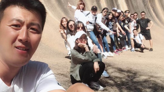 A man holds a selfie stick with a tour group.