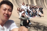 A man holds a selfie stick with a tour group.