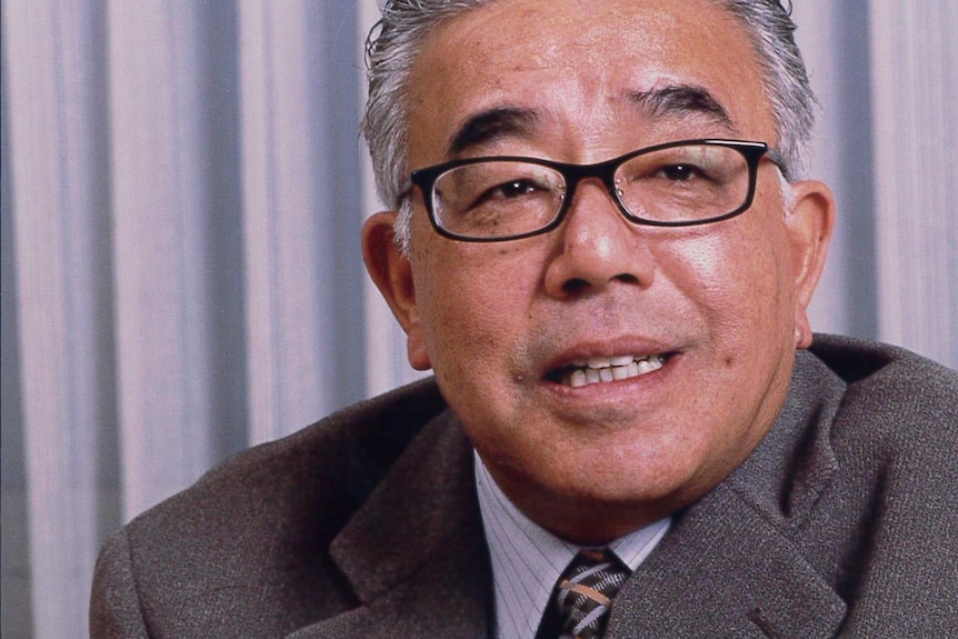 man wearing glasses has grey and white hair. Wearing grey suit