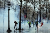 Demonstrators run away through tear gas during scuffles on the Champs-Elysees avenue in Paris.