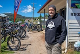 A man standing in front of a bike hire store.