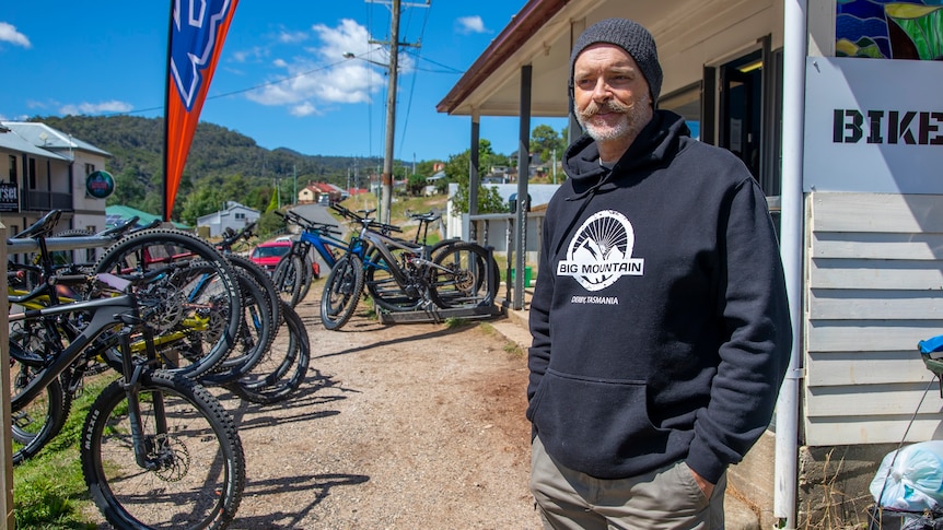 A man standing in front of a bike hire store.