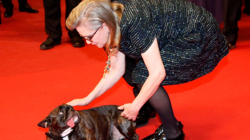Actress Carrie Fisher caresses her dog on the red carpet.