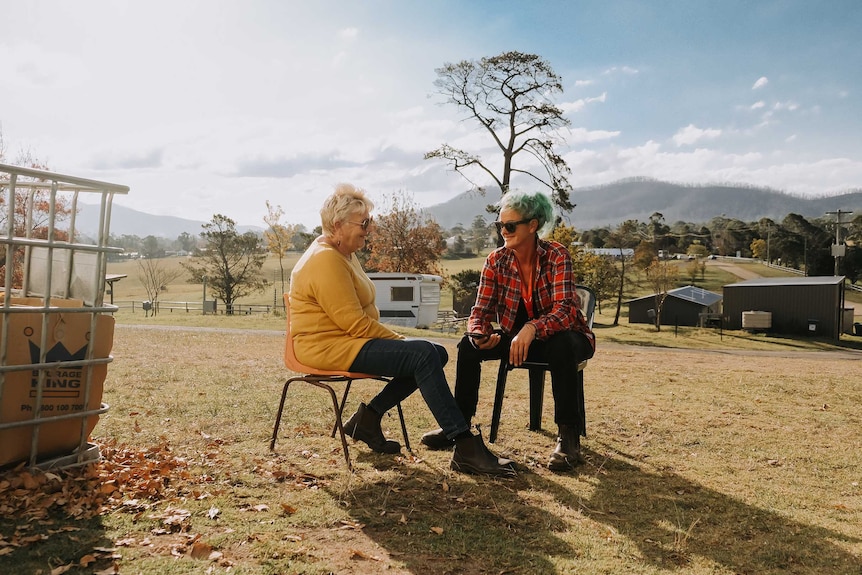 Cobargo bushfire relief centre volunteer coordinators Chris Walters and Danielle Murphy sit outside on chairs.