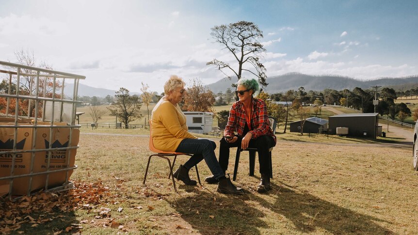 Cobargo bushfire relief centre volunteer coordinators Chris Walters and Danielle Murphy sit outside on chairs.