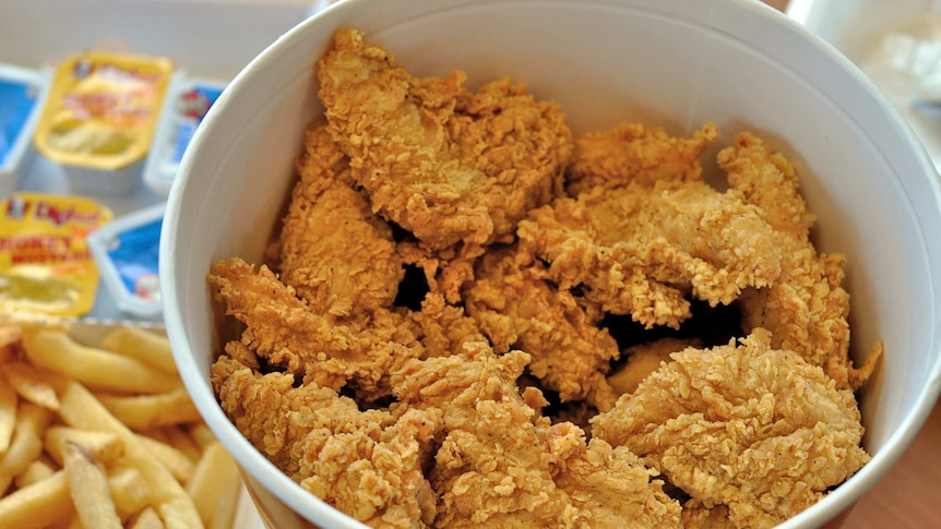 A box of fried chicken from KFC with chips on the side.