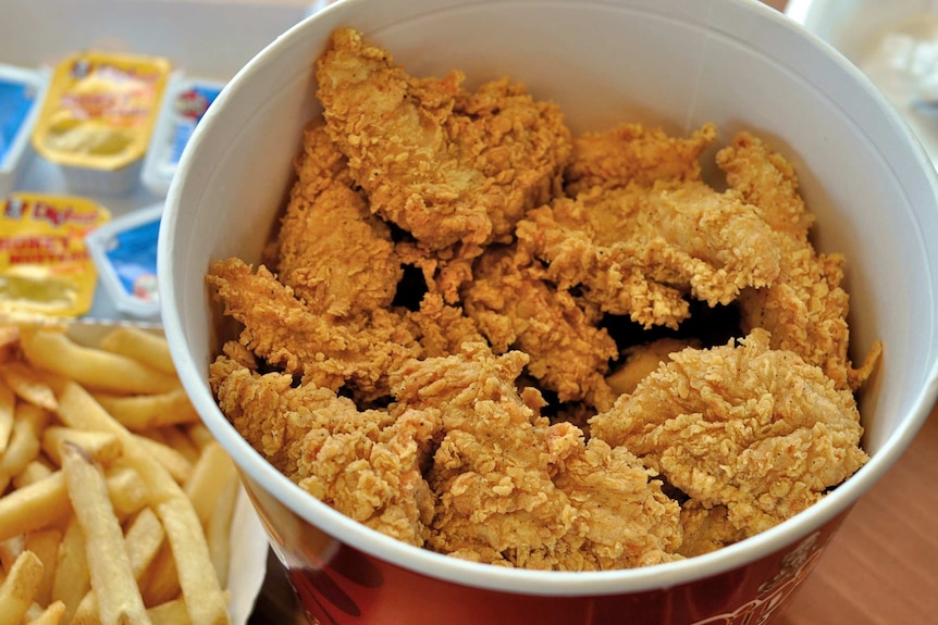 A box of fried chicken from KFC with chips on the side.