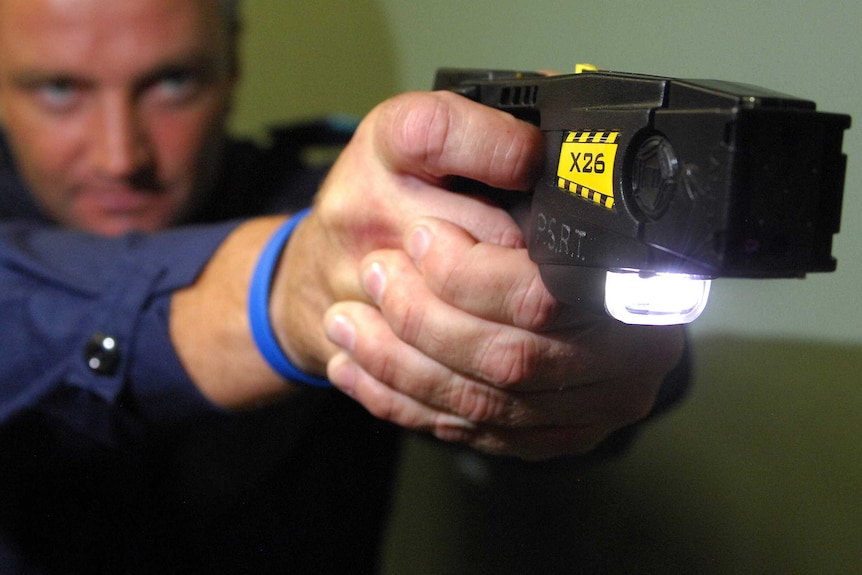 A police officer pointing a taser.