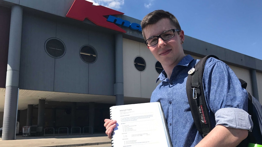 Job-seeker Mitchell Taylor holds up his resume outside K-Mart