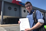 Job-seeker Mitchell Taylor holds up his resume outside K-Mart