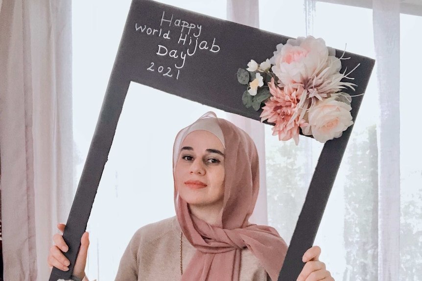 Laura Abdulfattah holds up a cut-out saying happy World Hijab Day.