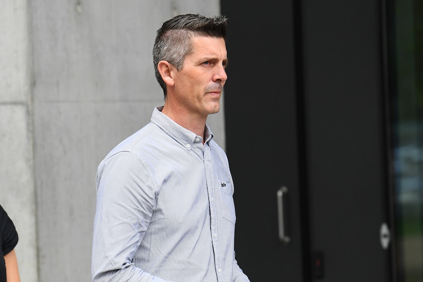 A man in a grey shirt outside court 