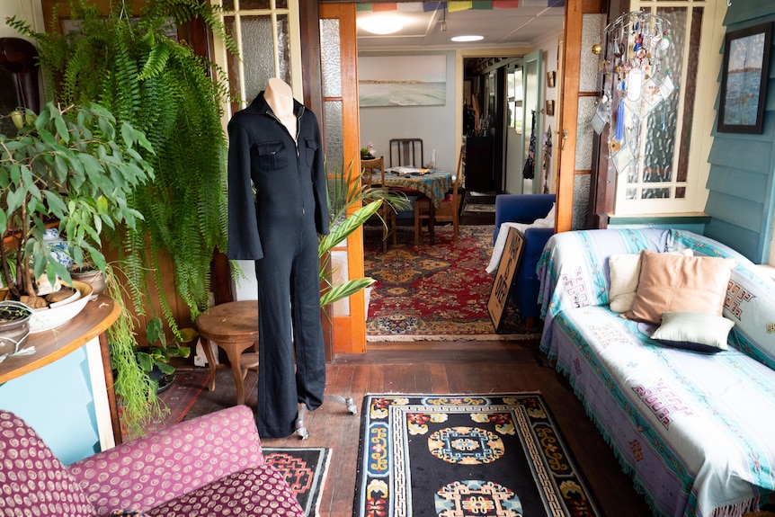 A retro black jumpsuits hands on a mannequin in a sun room. 