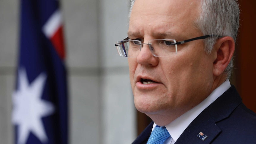 A close up of Prime Minister Scott Morrison, he is wearing a suit and pinned Australian flag broach.