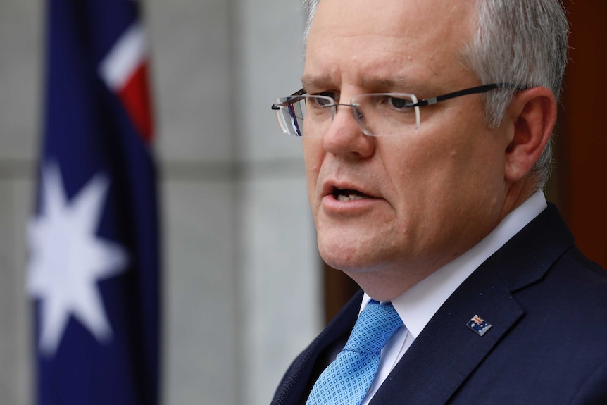 A close up of Prime Minister Scott Morrison, he is wearing a suit and pinned Australian flag broach.