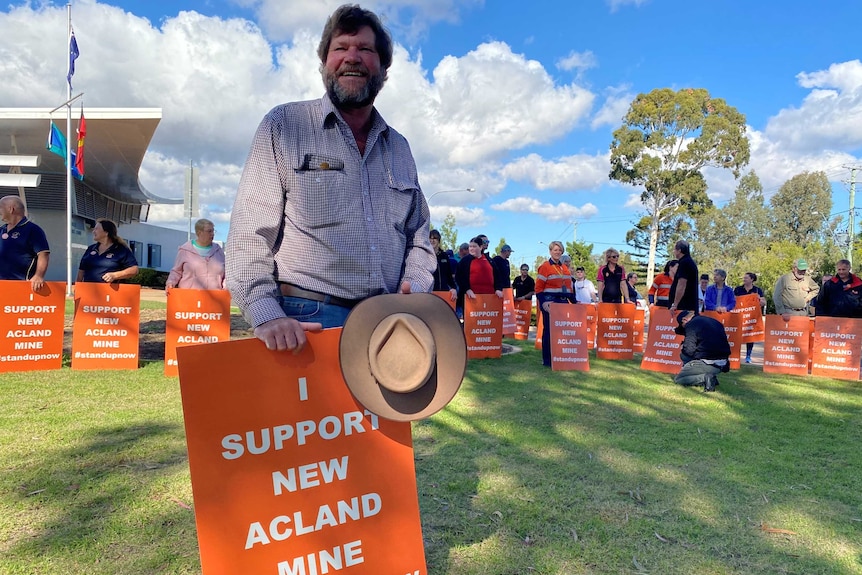 A man with an akubra and placard supporting the mine's approval.