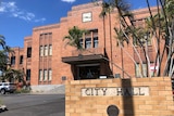 A large red brick building with a sign out the front that reads City Hall