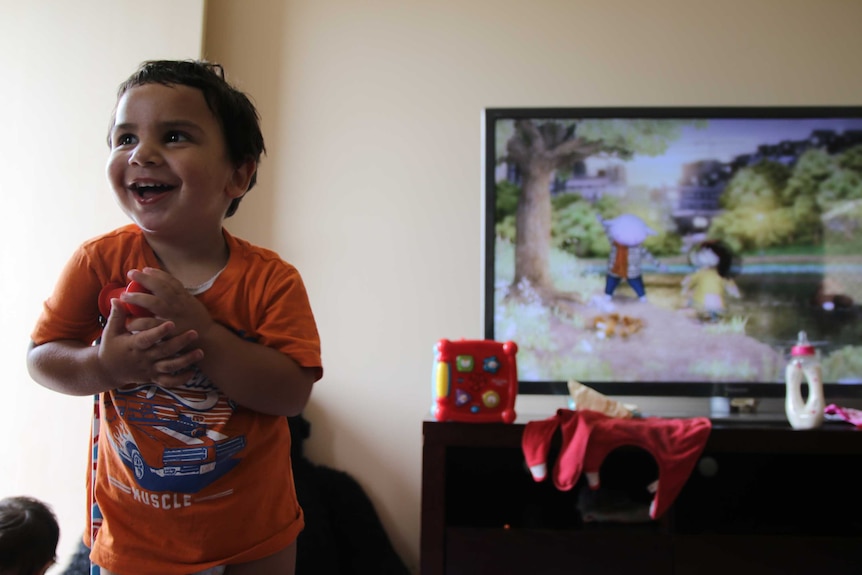 Two-year-old Nayte Slater laughs and clutches a toy at the Gomeroi gaaynggal centre in Tamworth.