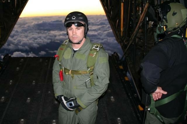 Tony standing near the open cavity of a plane above the clouds.