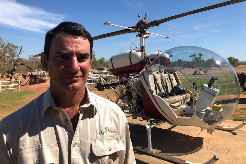 John Armstrong is standing in front of a helicopter on his property in Katherine, NT.