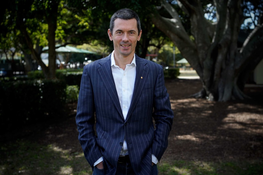 A man stands in front of a tree and smiles for the camera.