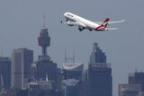 A jet takes off with the Sydney CBD in the background