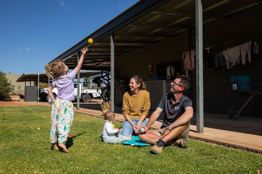 A young family soak up some sunshine in their backyard outside of Alice Springs.