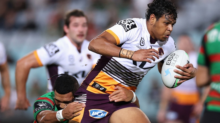 A rugby league player surges past defenders