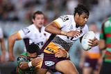 A rugby league player surges past defenders