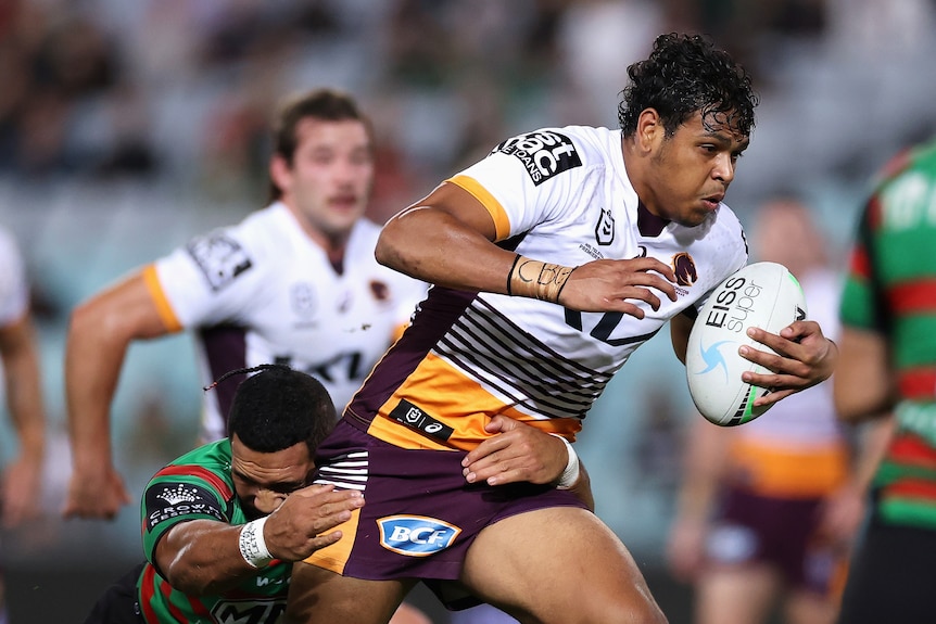 A rugby league player surges past defenders