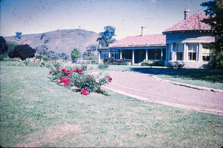 The front of a Spanish style home with driveway and rose garden