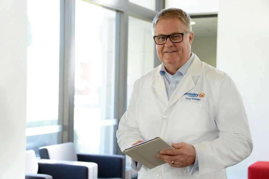 A man poses for a photo wearing a lab coat.