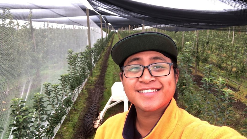 Jamson Agin stands in front of an orchard