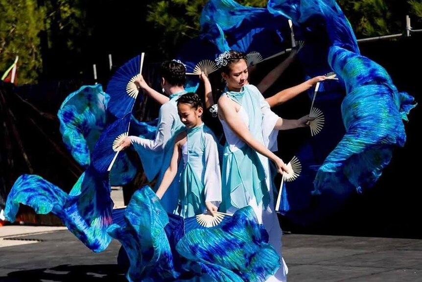Chinese dancers with bright blue fans.