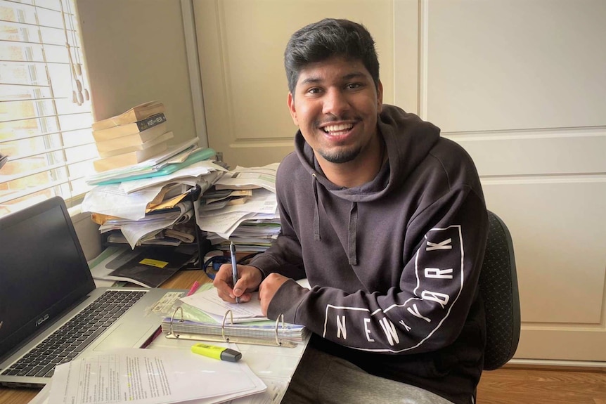 Ankit Bailwal sits at his desk at home studying
