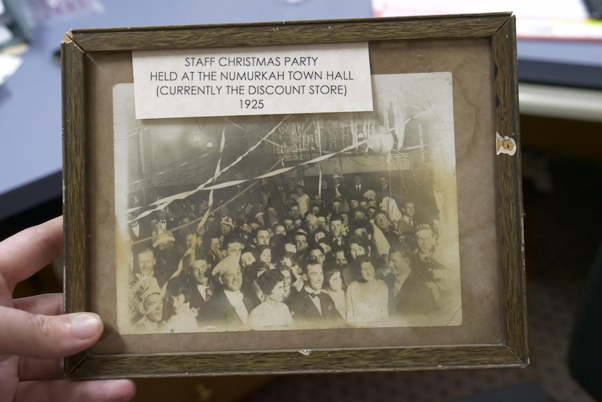 A small framed black and white photo from 1925 of a group of people at a christmas party 