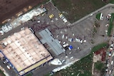 A satellite image shows people waiting in queues outside a large  building