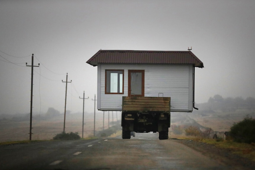 A family drives a truck loaded with a small house along a highway as they leave Nagorno-Karabakh in November 2020