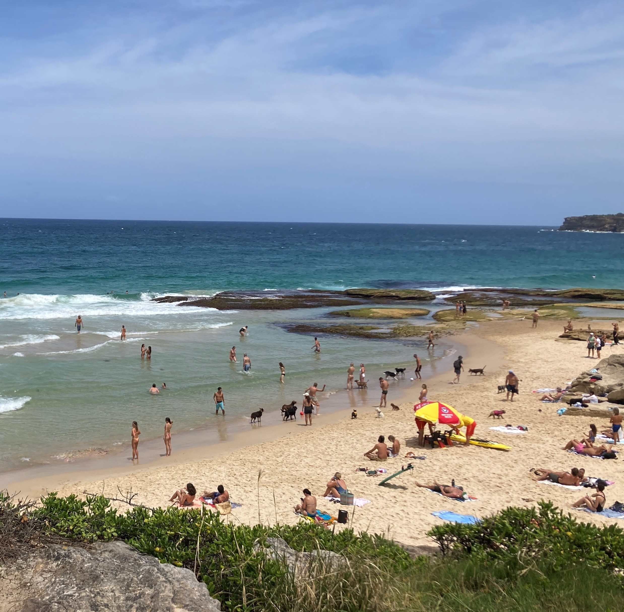 People on the sand and water with life savers under an umbrella on Mackenzies Bay beach