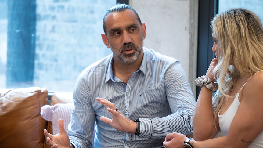 A man speaks to a woman next to him.