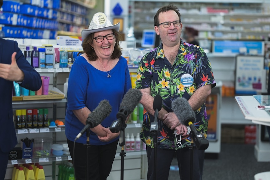 A man and woman in colourful clothing inside a pharmacy.