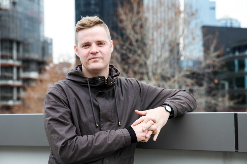 Colour photography of Atheist comedian Tom Ballard standing on a city rooftop.