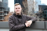 Colour photography of Atheist comedian Tom Ballard standing on a city rooftop.