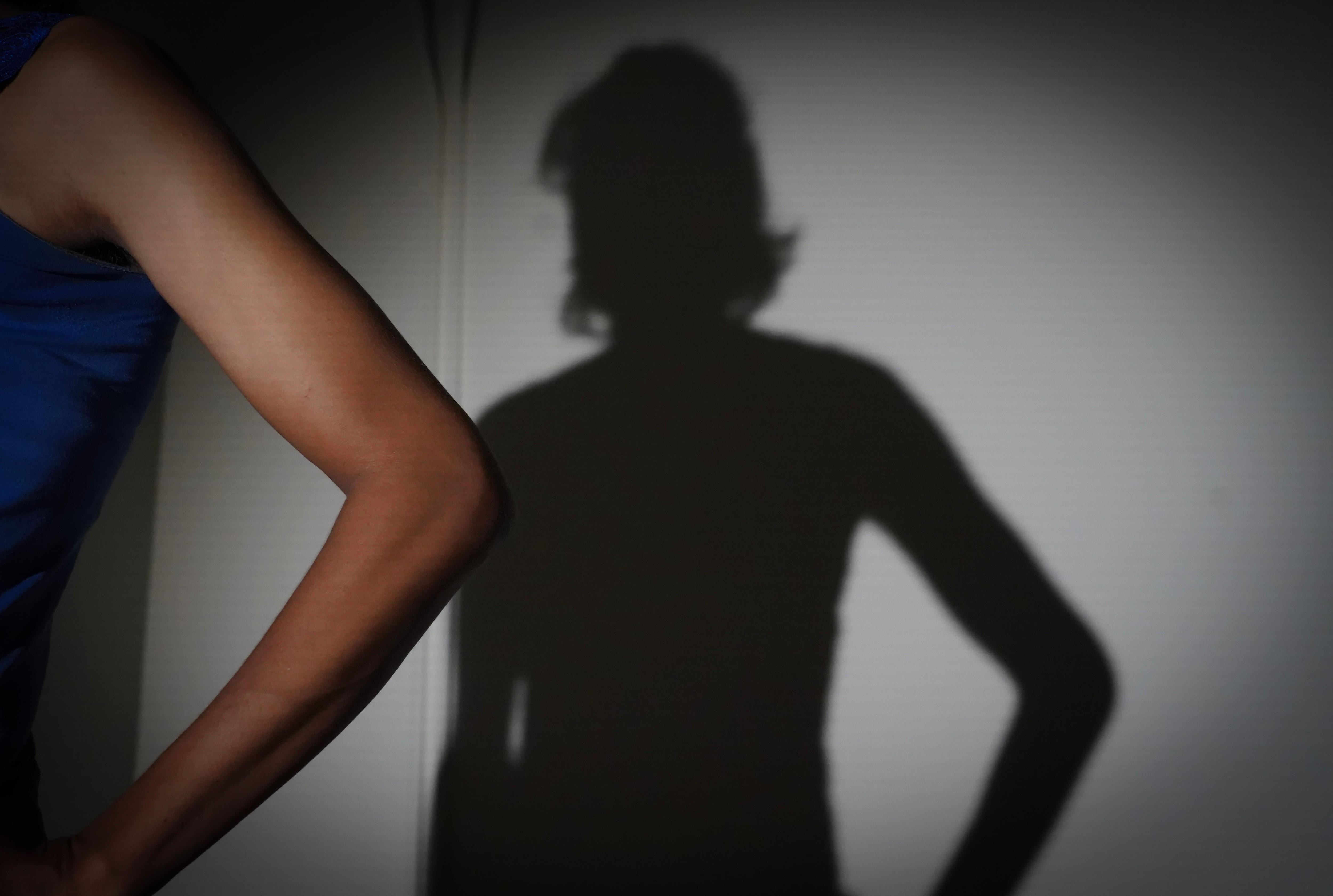 O braço de uma mulher com sua sombra na parede do fundo.