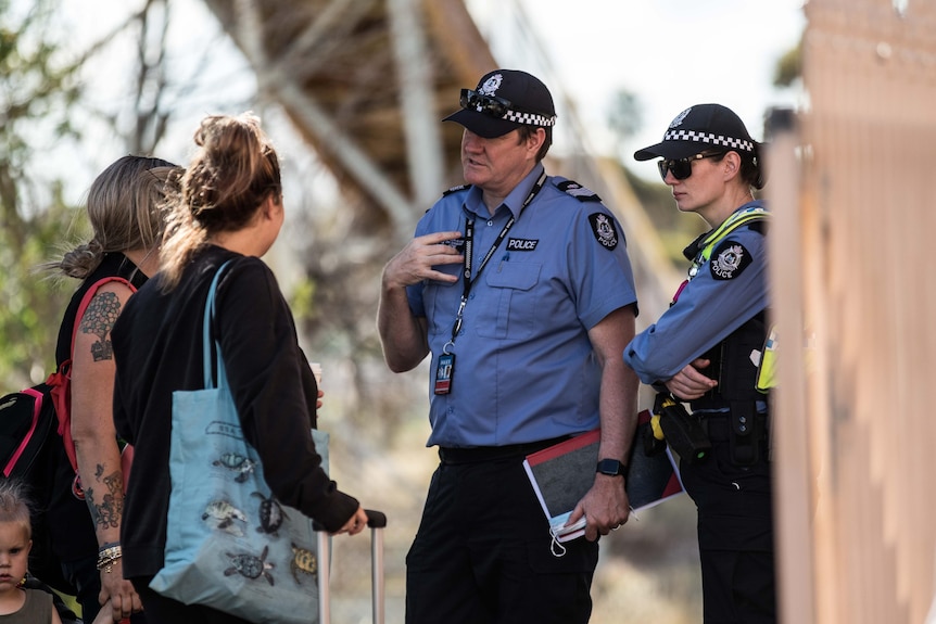 Police speak with passengers on a train platform